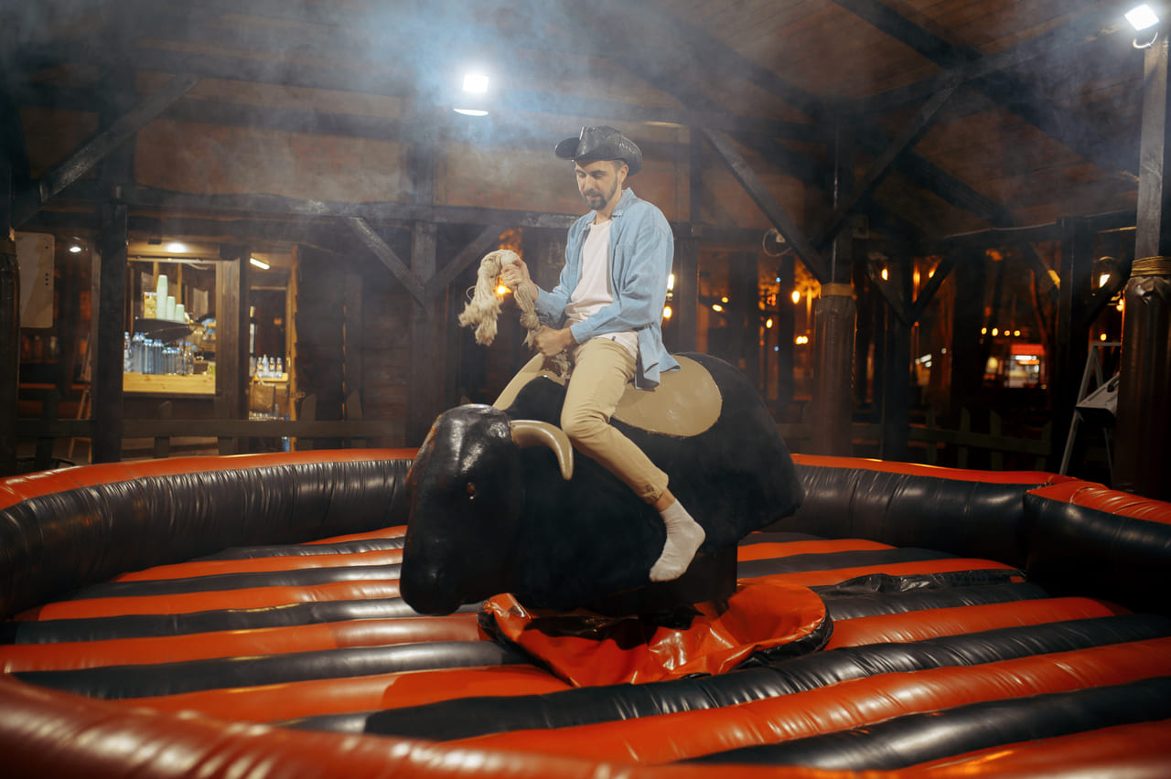 man-on-rodeo-attraction-in-night-amusement-park-2024-12-04-12-20-32-utc