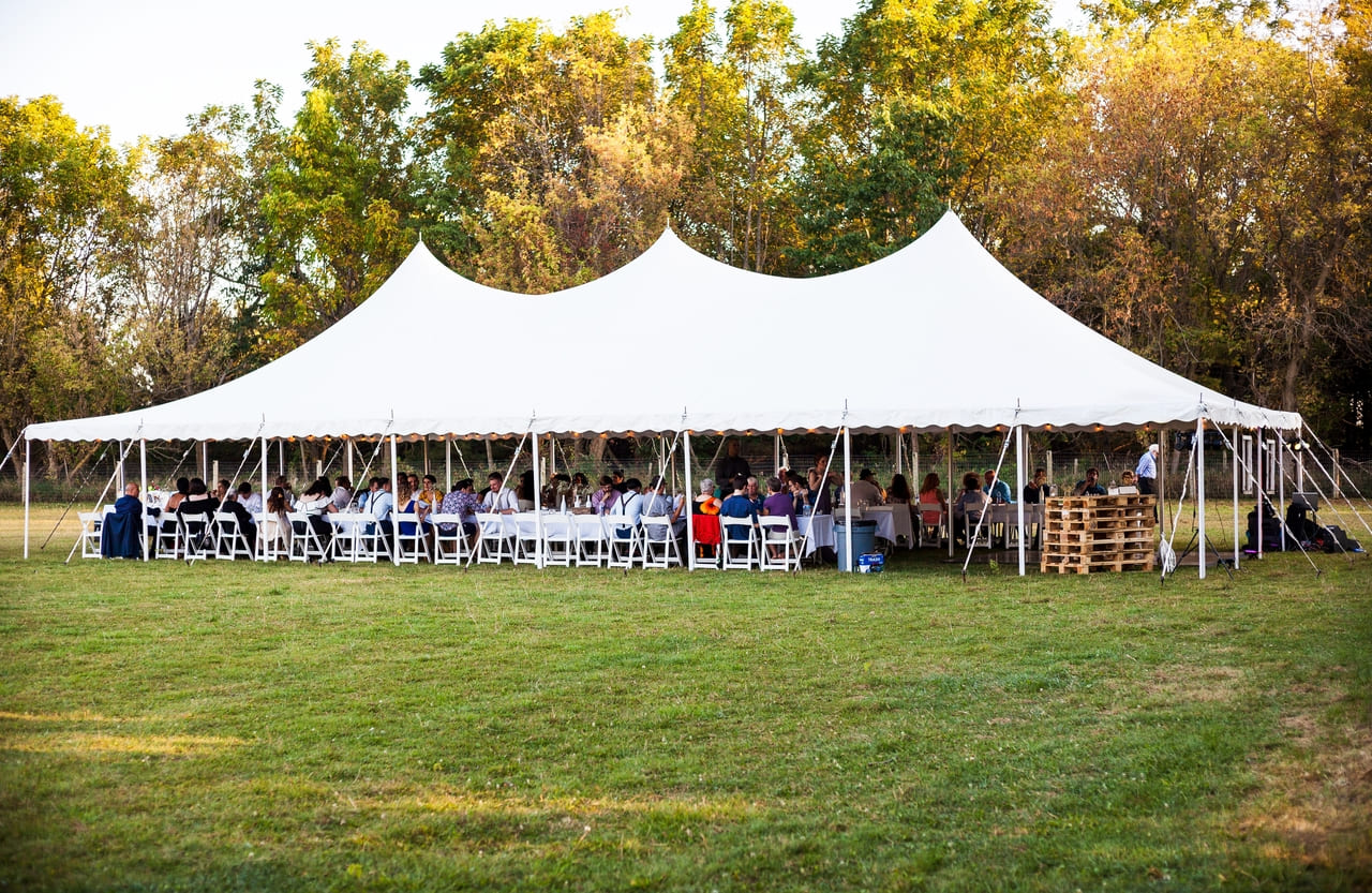 white-outdoor-tent-full-of-tables-and-people-seate-2024-09-15-18-50-18-utc