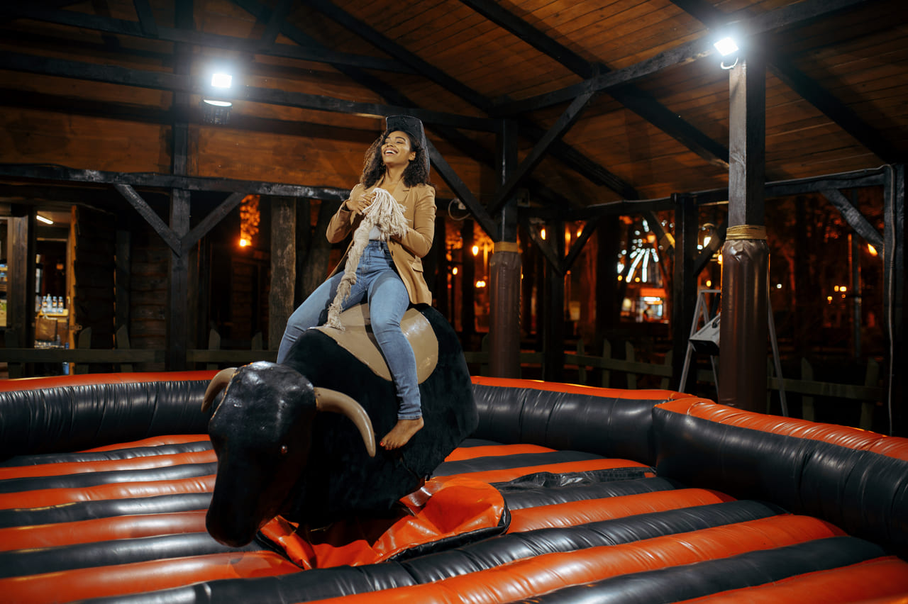 woman-on-rodeo-attraction-in-night-amusement-park-2024-12-02-23-48-32-utc